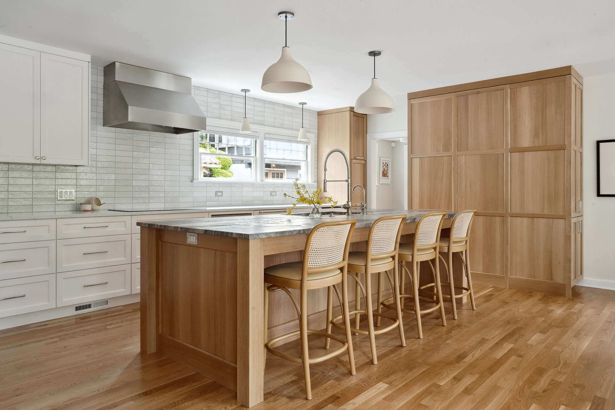 Remodeled kitchen with white oak island and tall storage wall, cane barstools and leathered granite countertop, Arlington Heights Remodel by Tweto Architecture