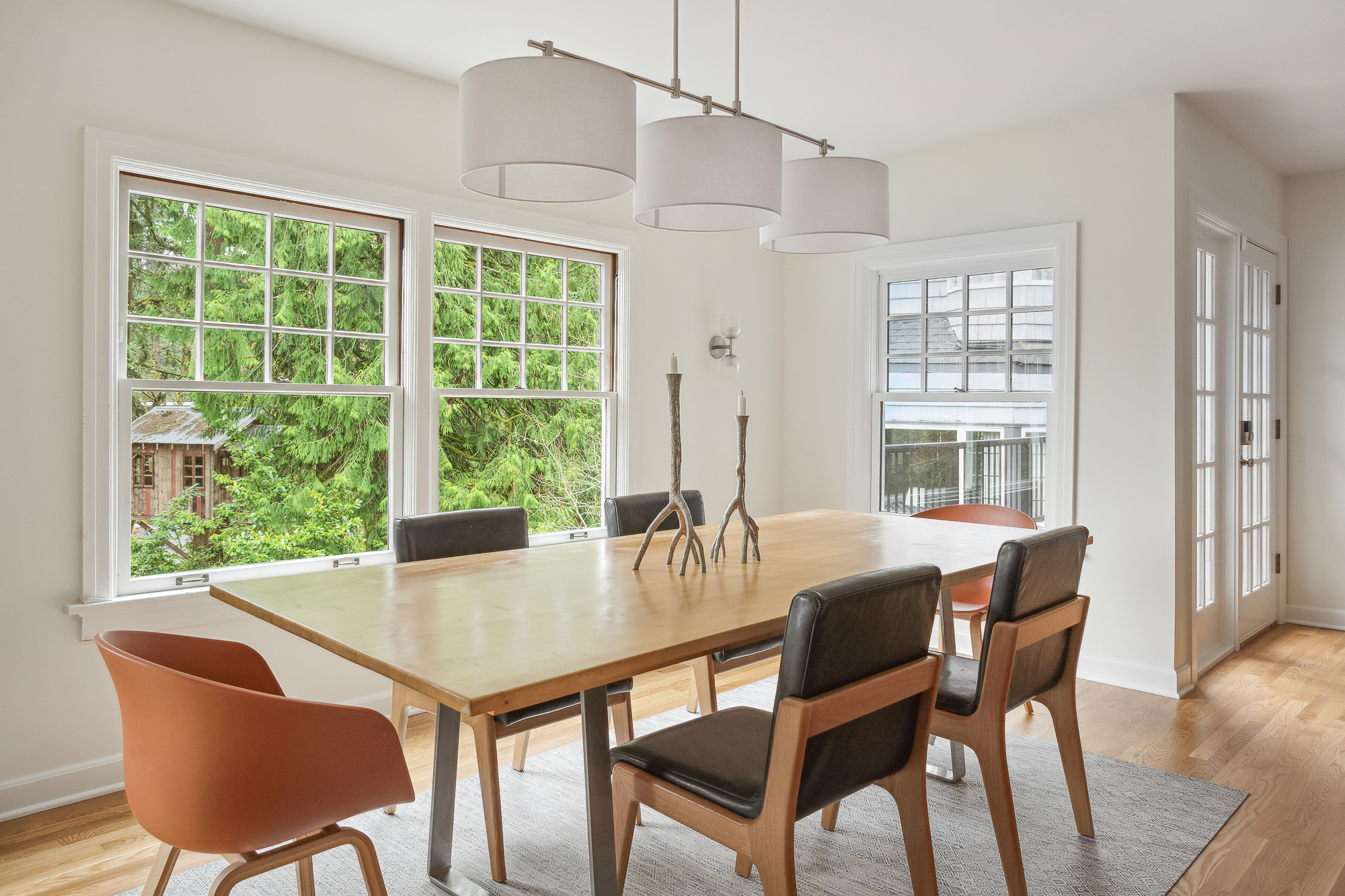 Bright dining room with large south-facing windows and views to trees, drum pendant lights over wood dining table, Arlington Heights Remodel by Tweto Architecture