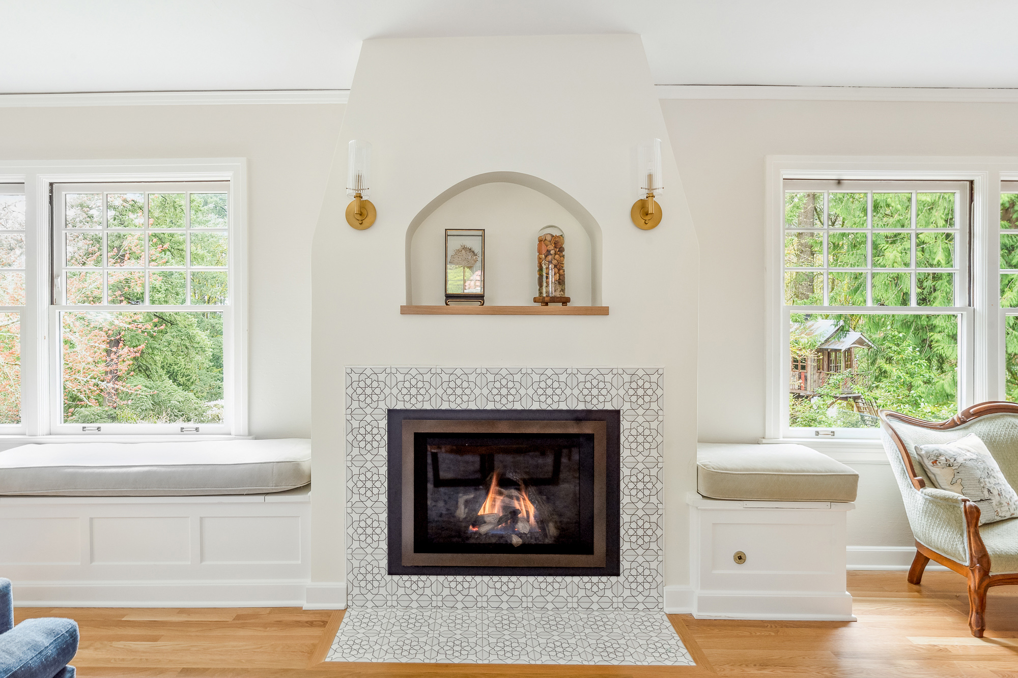 Gas fireplace with patterned tile surround and arched plaster niche above, flanked by window seats and views to garden, Arlington Heights Remodel by Tweto Architecture