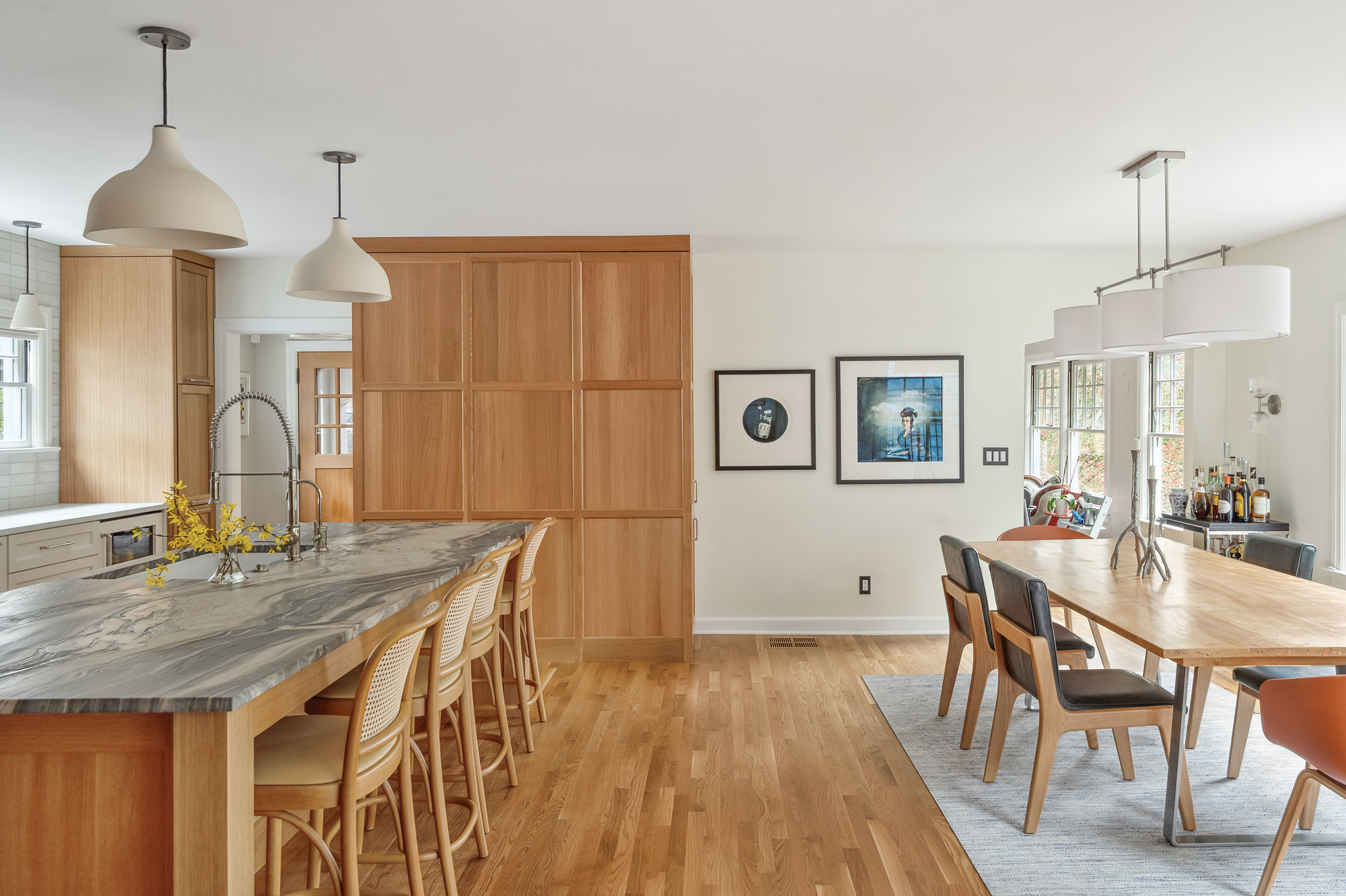 Remodeled kitchen and dining room open to each other, island with seating at left and dining table at right, Arlington Heights Remodel by Tweto Architecture