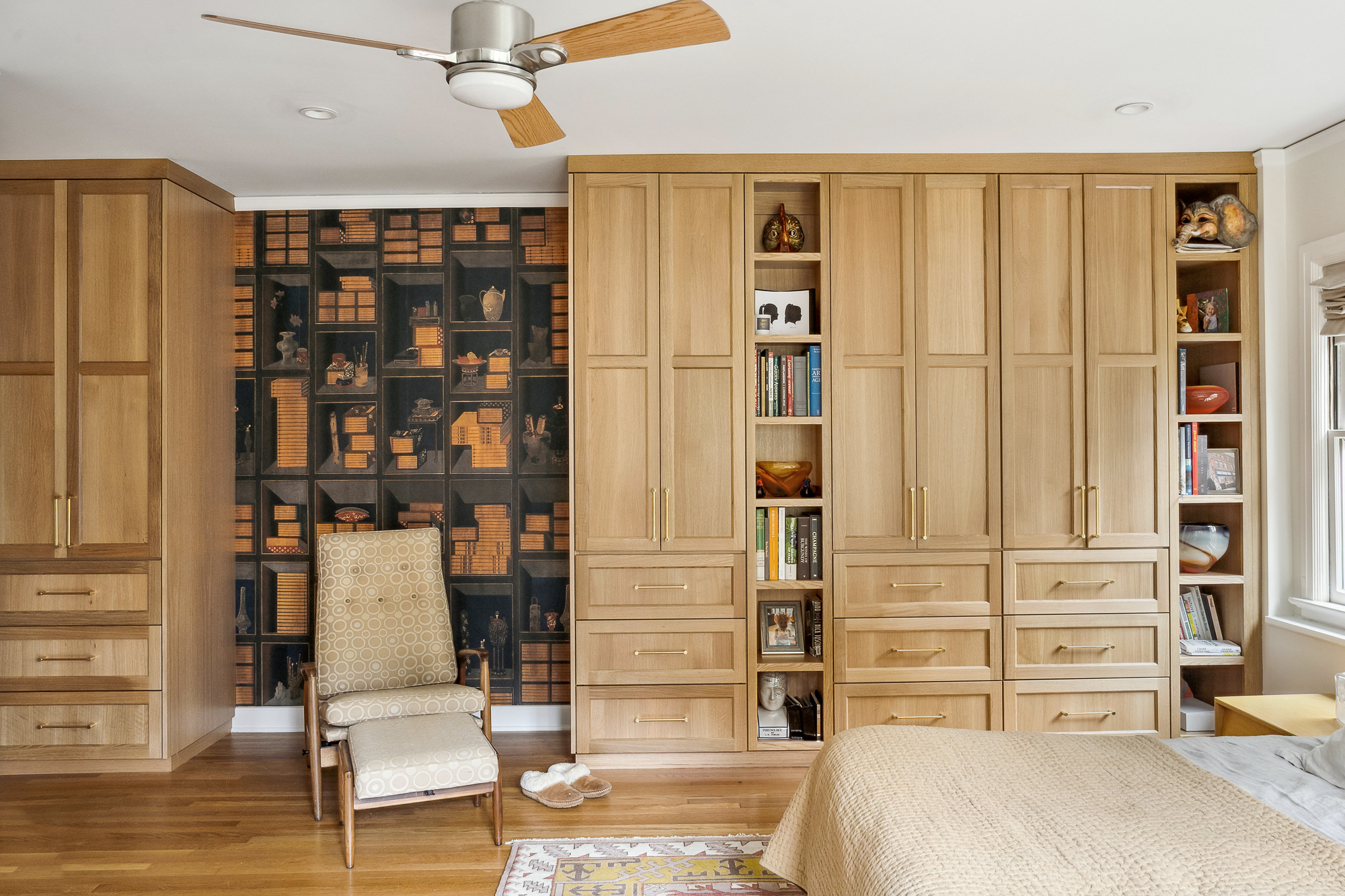 Primary bedroom with floor-to-ceiling white oak built-in wardrobe and open shelving, decorative wallpaper panel behind reading chair, Arlington Heights Remodel by Tweto Architecture