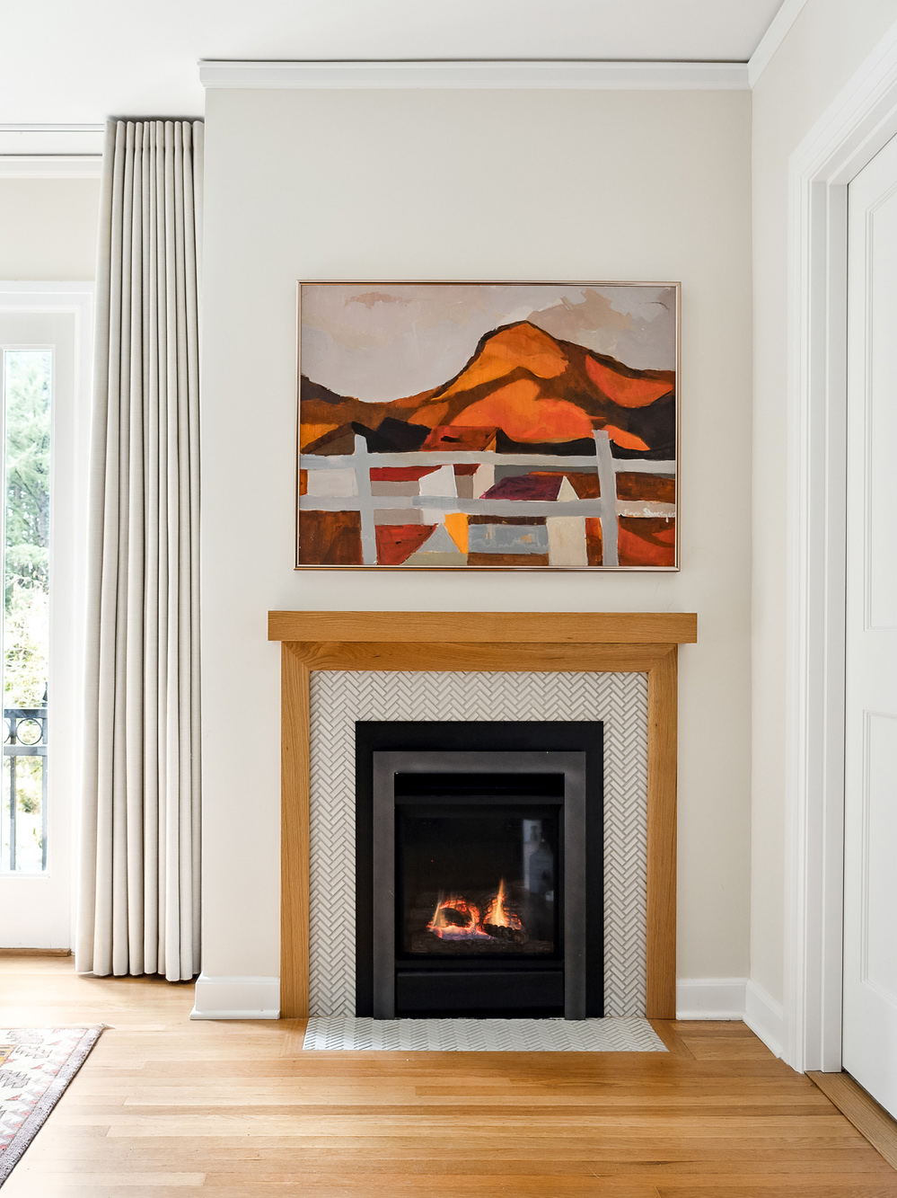 Primary bedroom gas fireplace with herringbone tile surround and white oak mantel, landscape painting above, Arlington Heights Remodel by Tweto Architecture