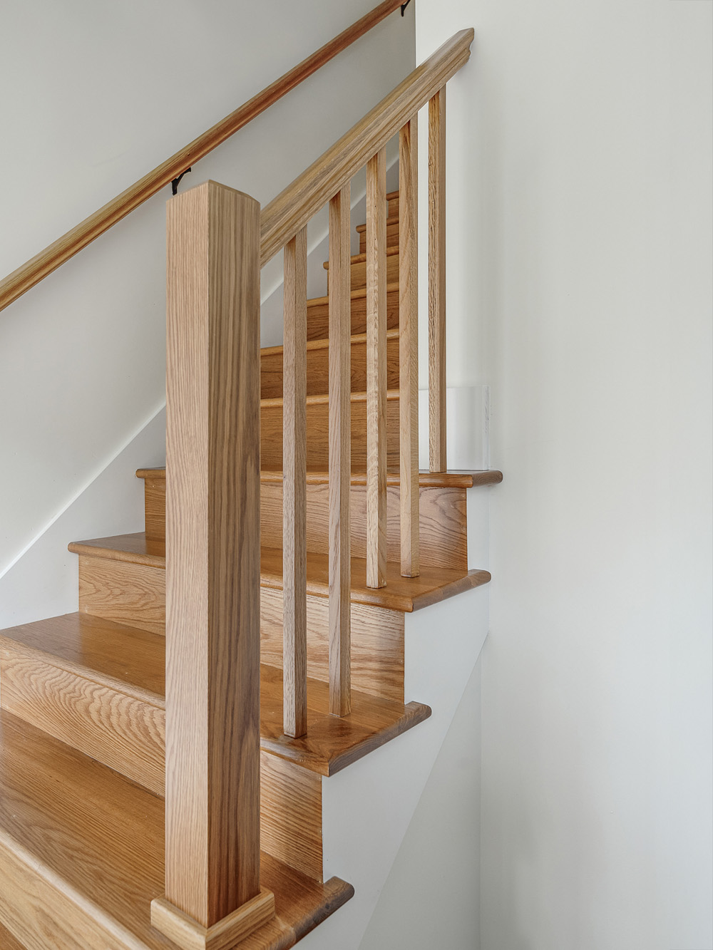 Close-up of rebuilt white oak stair treads and square balusters showing wood grain and joinery detail, Arlington Heights Remodel by Tweto Architecture