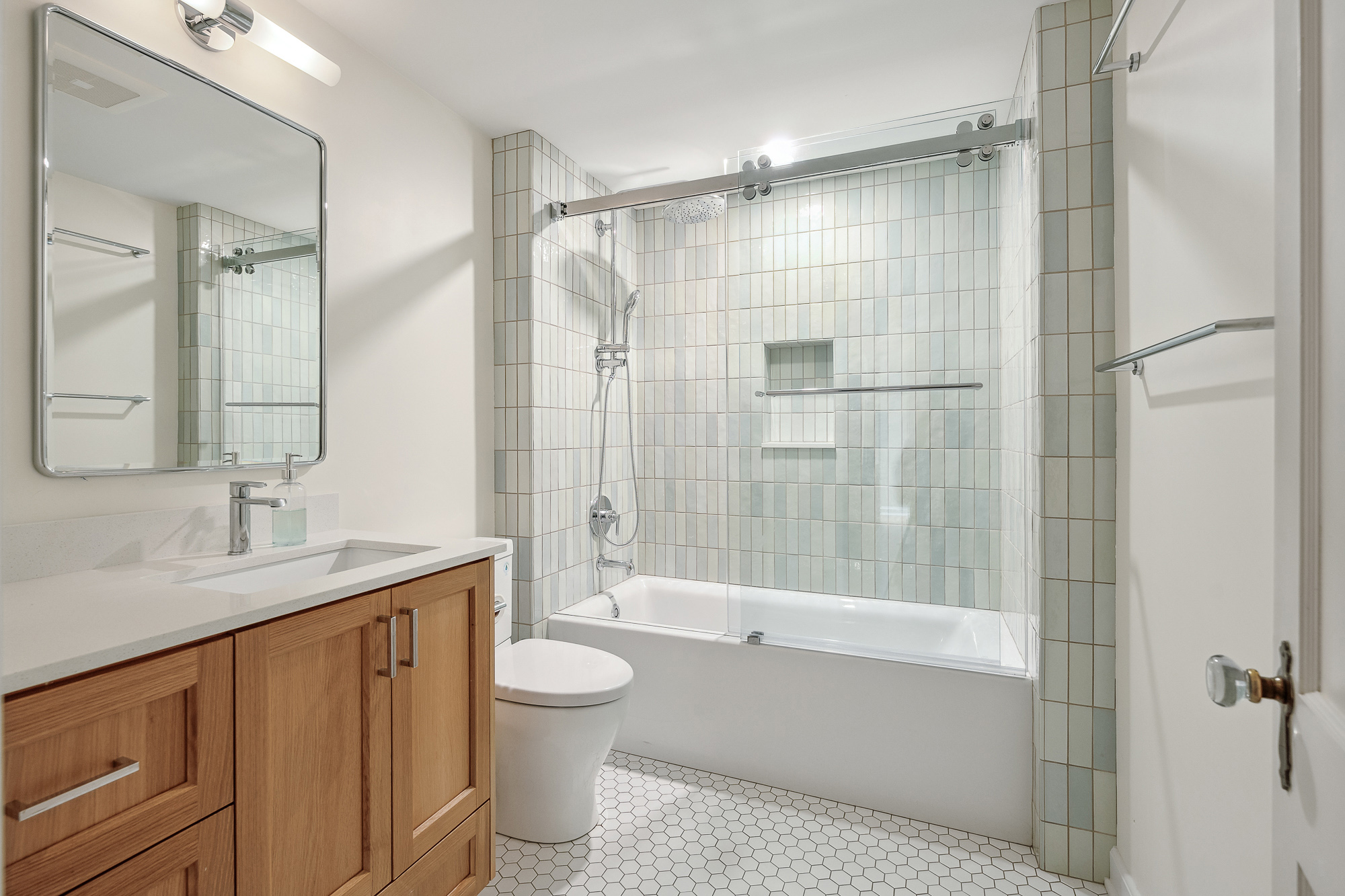 Secondary bathroom with tub-shower and iridescent square tile surround, oak vanity and hexagonal tile floor, Arlington Heights Remodel by Tweto Architecture