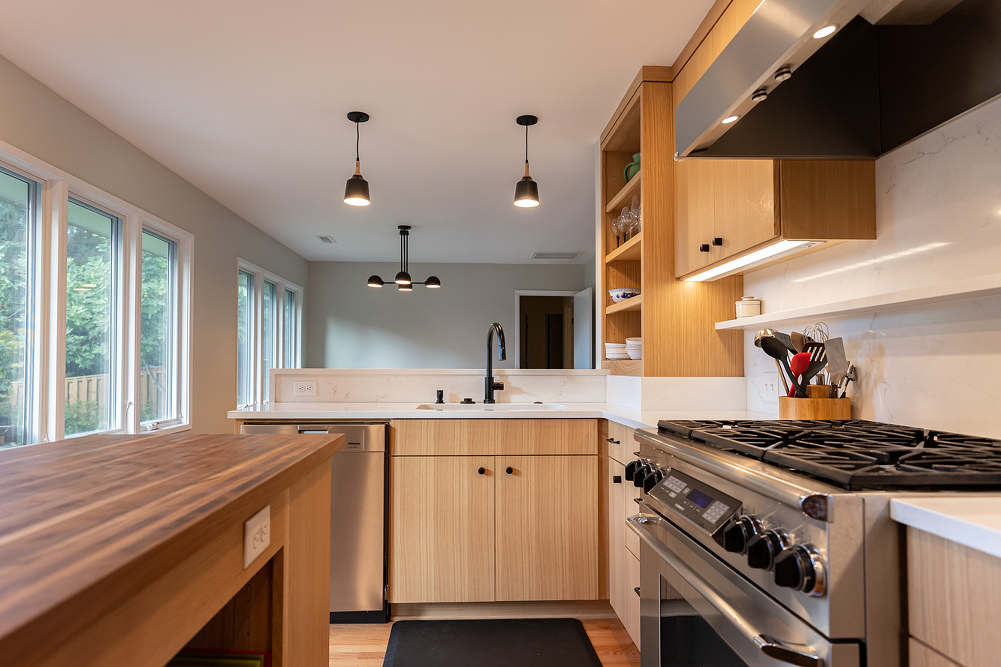 New kitchen looking from walnut island toward range and open shelves, south casement windows at left, Brooklyn Street remodel by Tweto Architecture, SE Portland