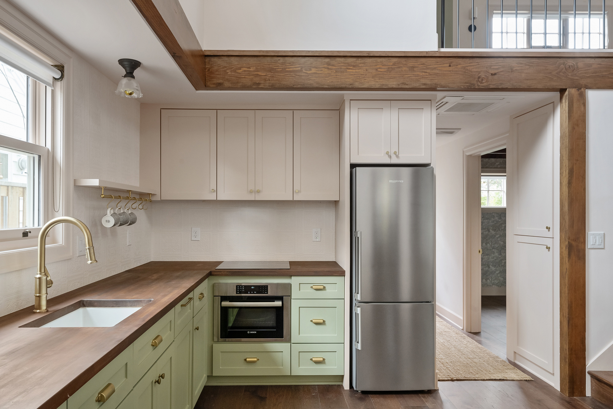 Kitchen with green lower cabinets, cream upper cabinets, walnut countertop, and exposed wood beam framing the kitchen bump-out, Buckman ADU SE Portland by Tweto Architecture