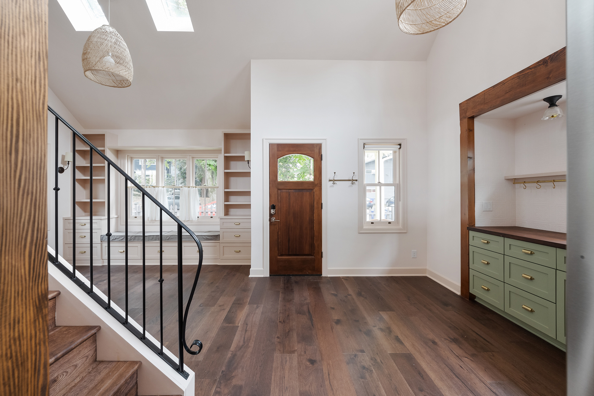 Open living area looking toward the front door, with built-in window seat and shelves flanking the street-facing windows and entry mudroom cabinetry at right, Buckman ADU SE Portland by Tweto Architecture
