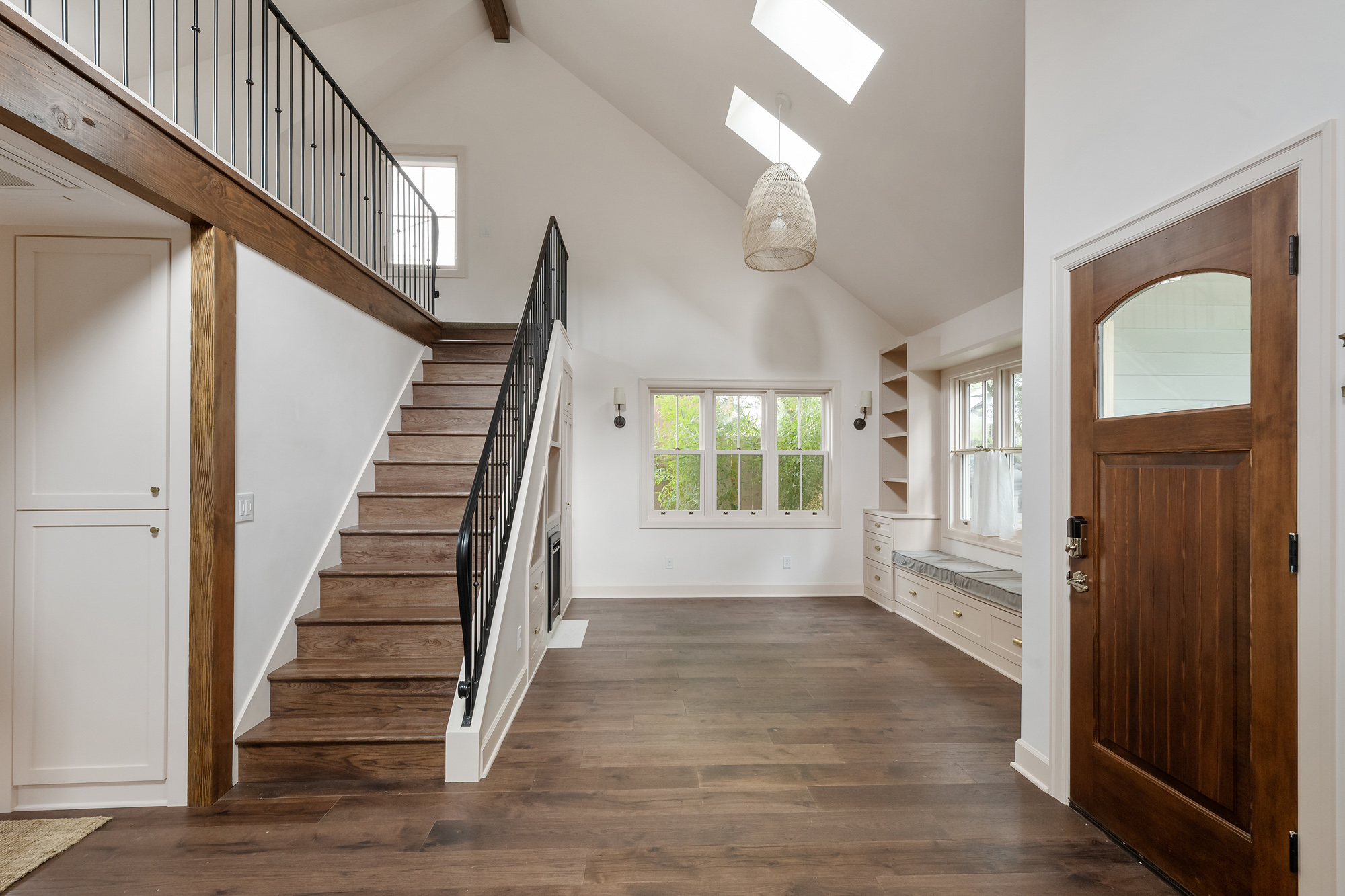 Vaulted main living area with skylights, stair at left, built-in window seat, and front door at right, Buckman ADU SE Portland by Tweto Architecture