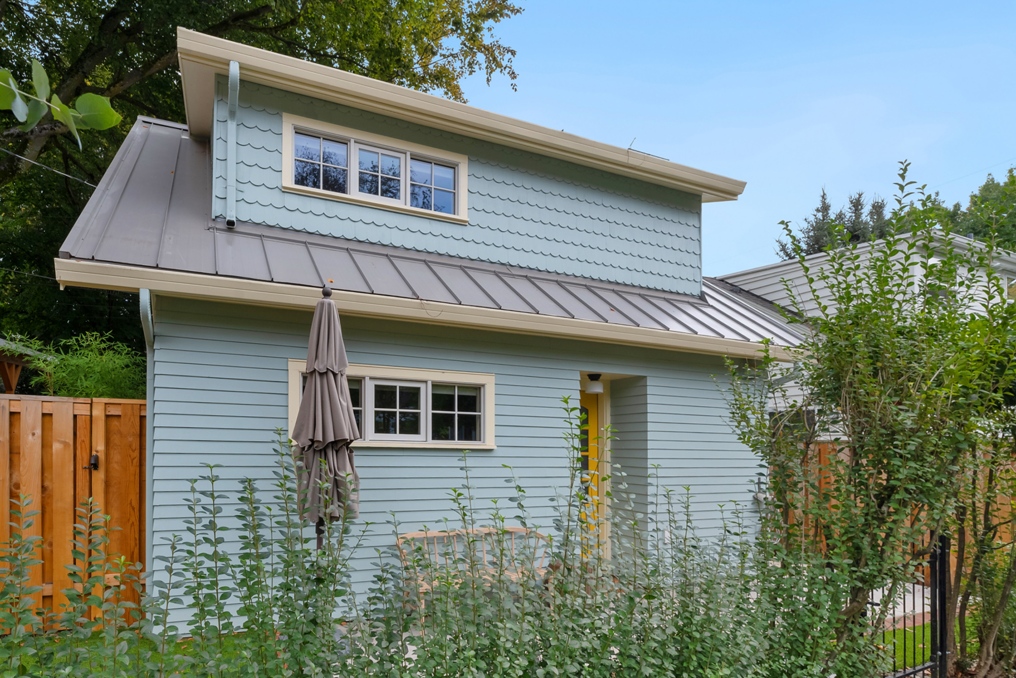 Buckman ADU rear elevation with blue-green fiber cement siding, metal roof, and yellow back door, SE Portland by Tweto Architecture