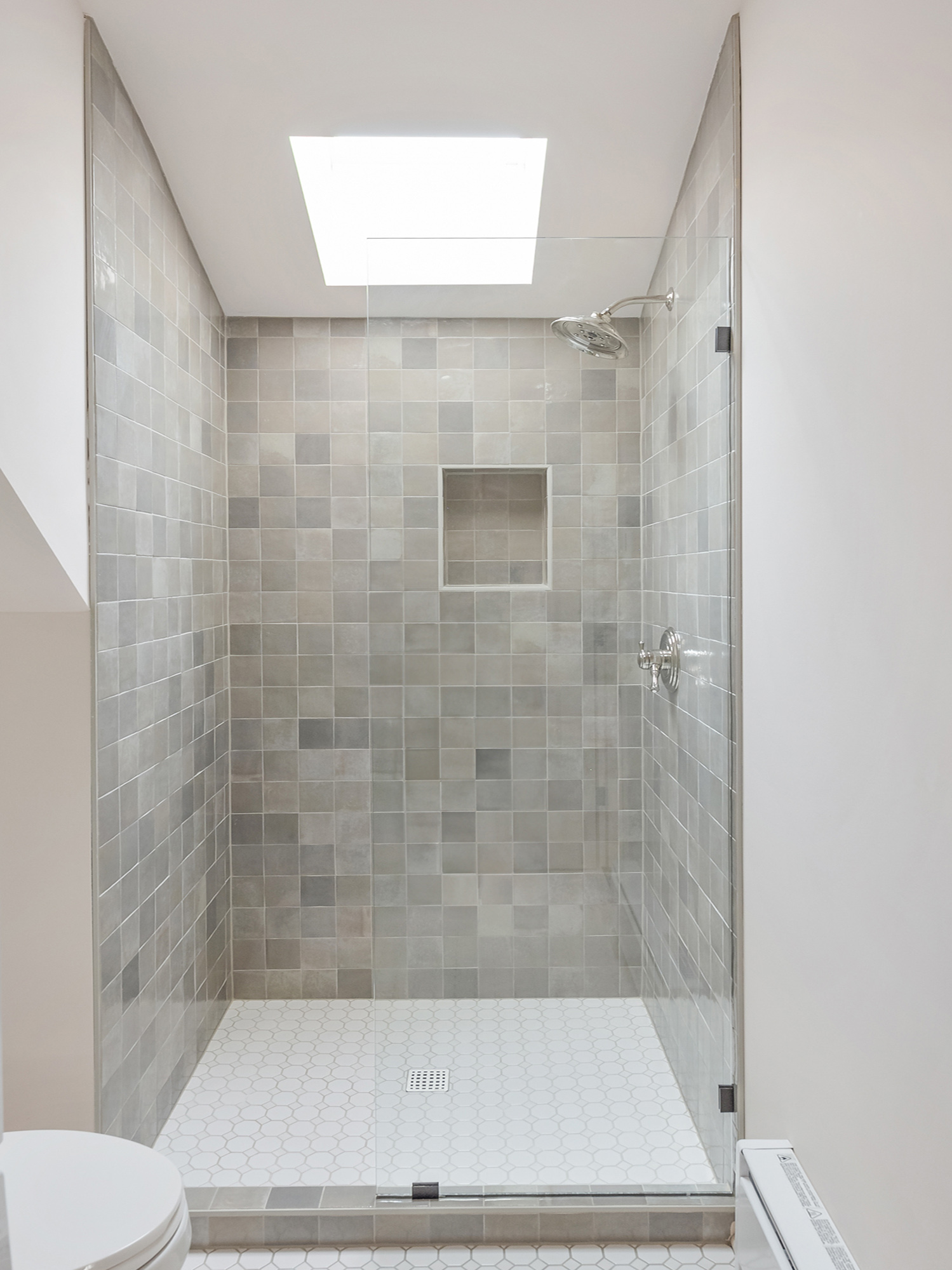 Tile shower with grey square zellige tile, glass door, and skylight above, Buckman ADU SE Portland by Tweto Architecture