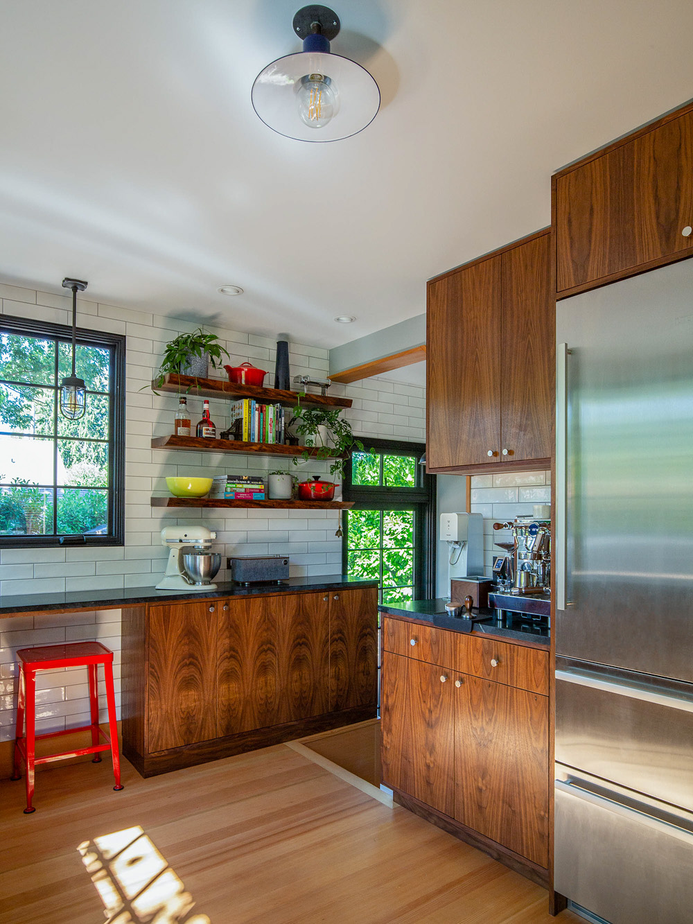 Kitchen viewed from the back showing walnut cabinets, open shelving, and stainless refrigerator, Concordia Kitchen by Tweto Architecture