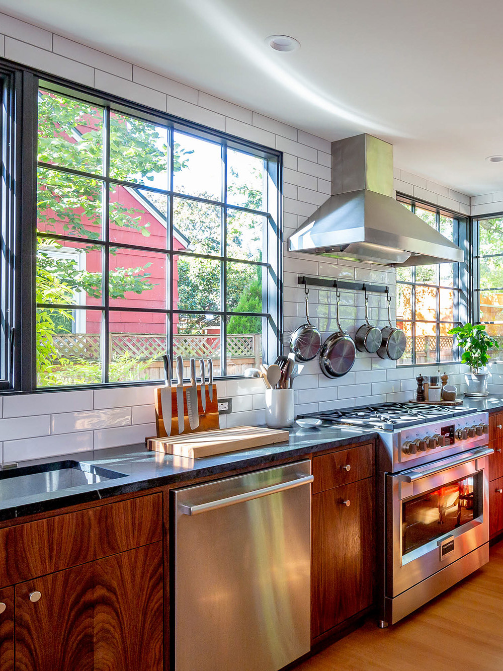 Remodeled kitchen with commercial range, walnut cabinets, and tall black-framed windows flooding the space with light, Concordia Kitchen by Tweto Architecture
