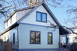 Two-story addition on a light blue clapboard house with dark trim, NE 12th addition in Portland by Tweto Architecture