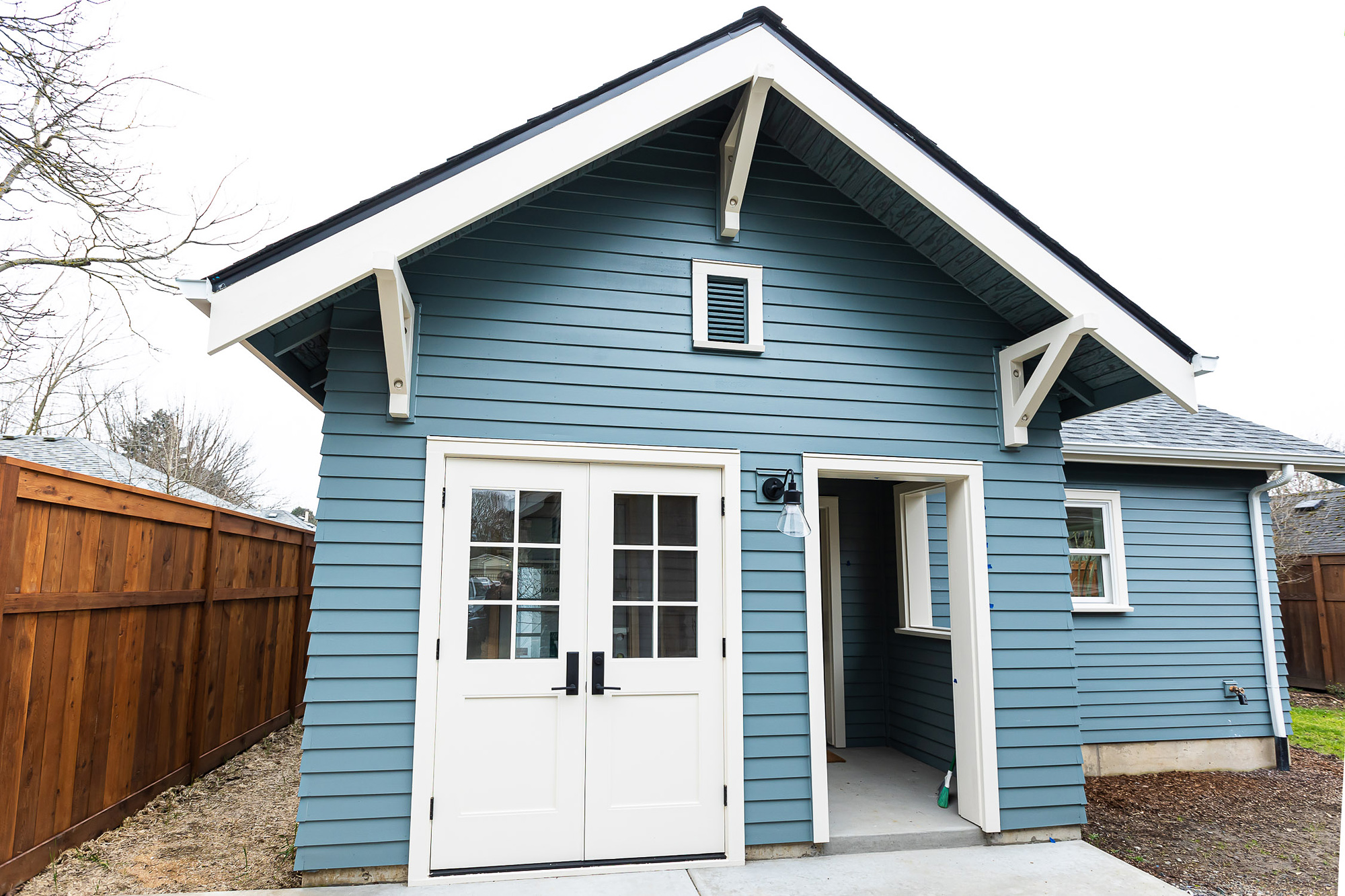 Irvington ADU front elevation with blue-grey lap siding, craftsman gable brackets, French doors, and covered entry porch, Irvington Historic District by Tweto Architecture