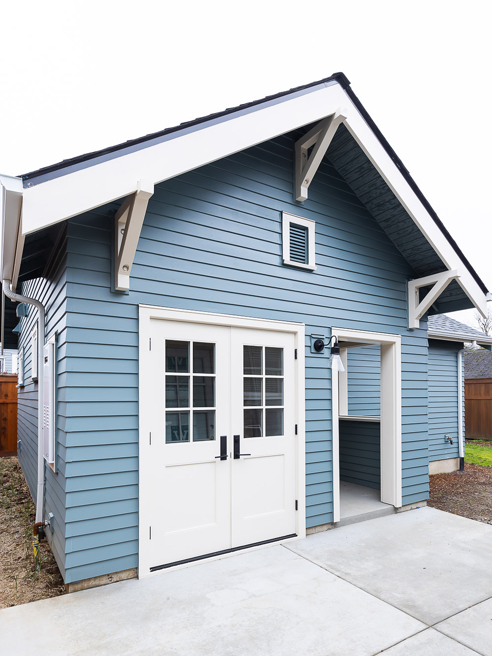 Front elevation of Irvington ADU with craftsman gable brackets, French doors with grille lights, and covered entry porch, by Tweto Architecture