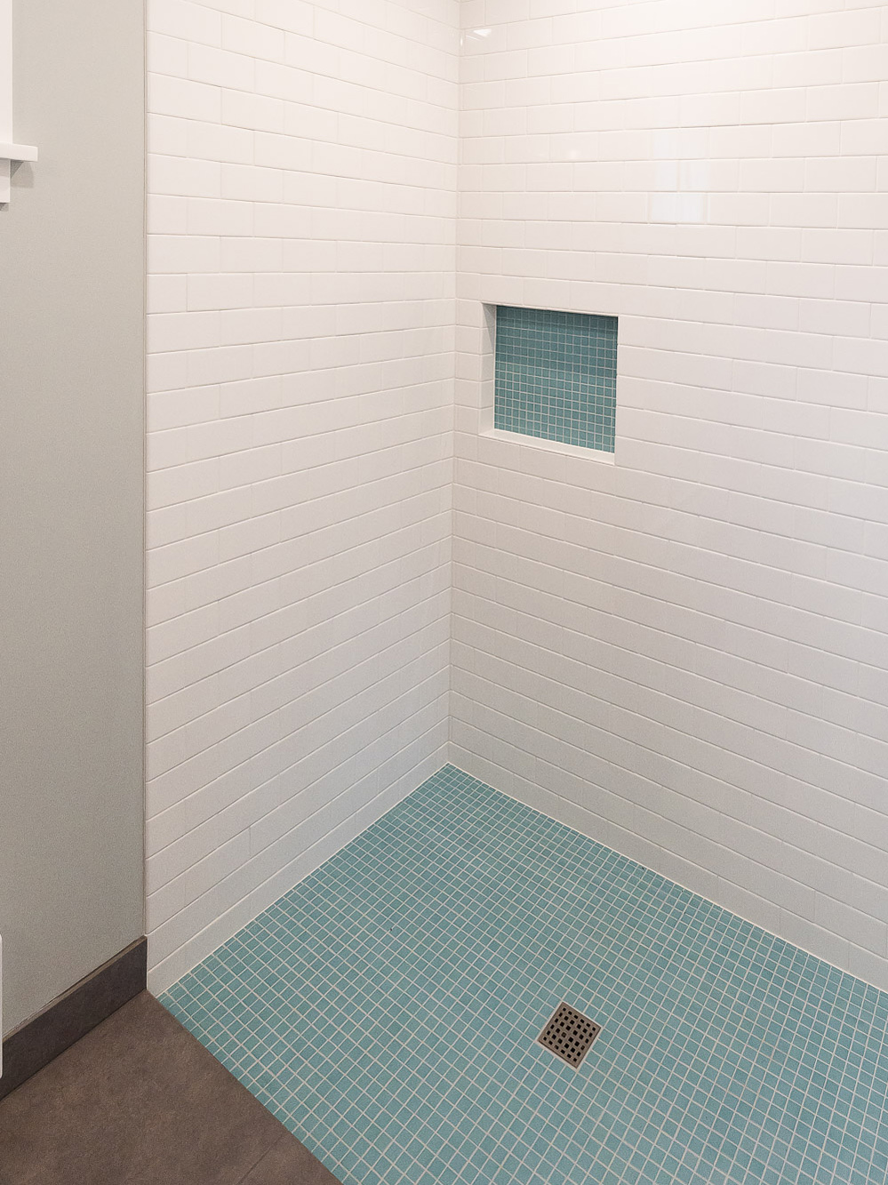 Walk-in shower with white subway tile walls, teal mosaic tile floor, and built-in niche with mosaic tile accent, Irvington ADU by Tweto Architecture