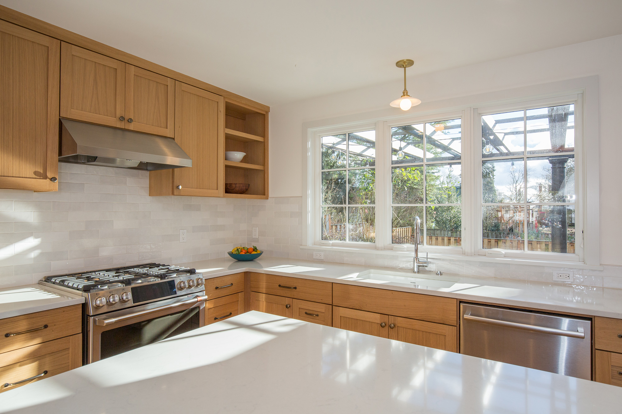 New kitchen toward sink and three south casement windows with backyard pergola beyond, Mt. Tabor Tudor remodel by Tweto Architecture, SE Portland