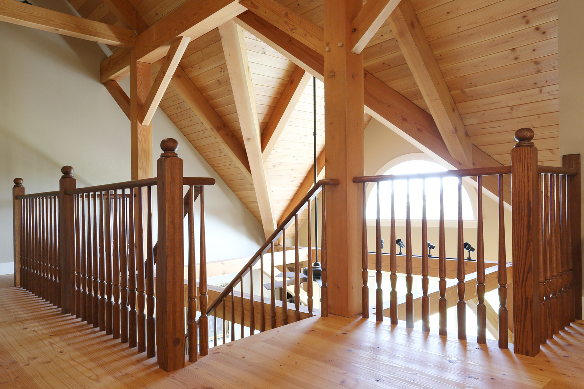 Open stair railing at loft level looking across to second floor landing with arched window and exposed Douglas Fir decking ceiling, North Plains Timber Frame by Tweto Architecture