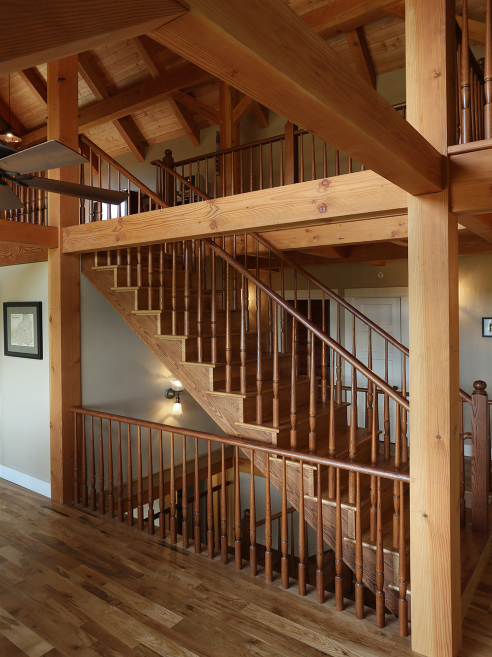 Open stair with wood balustrade rising from main floor through second floor to loft, timber frame columns and exposed decking visible at each level, North Plains Timber Frame by Tweto Architecture