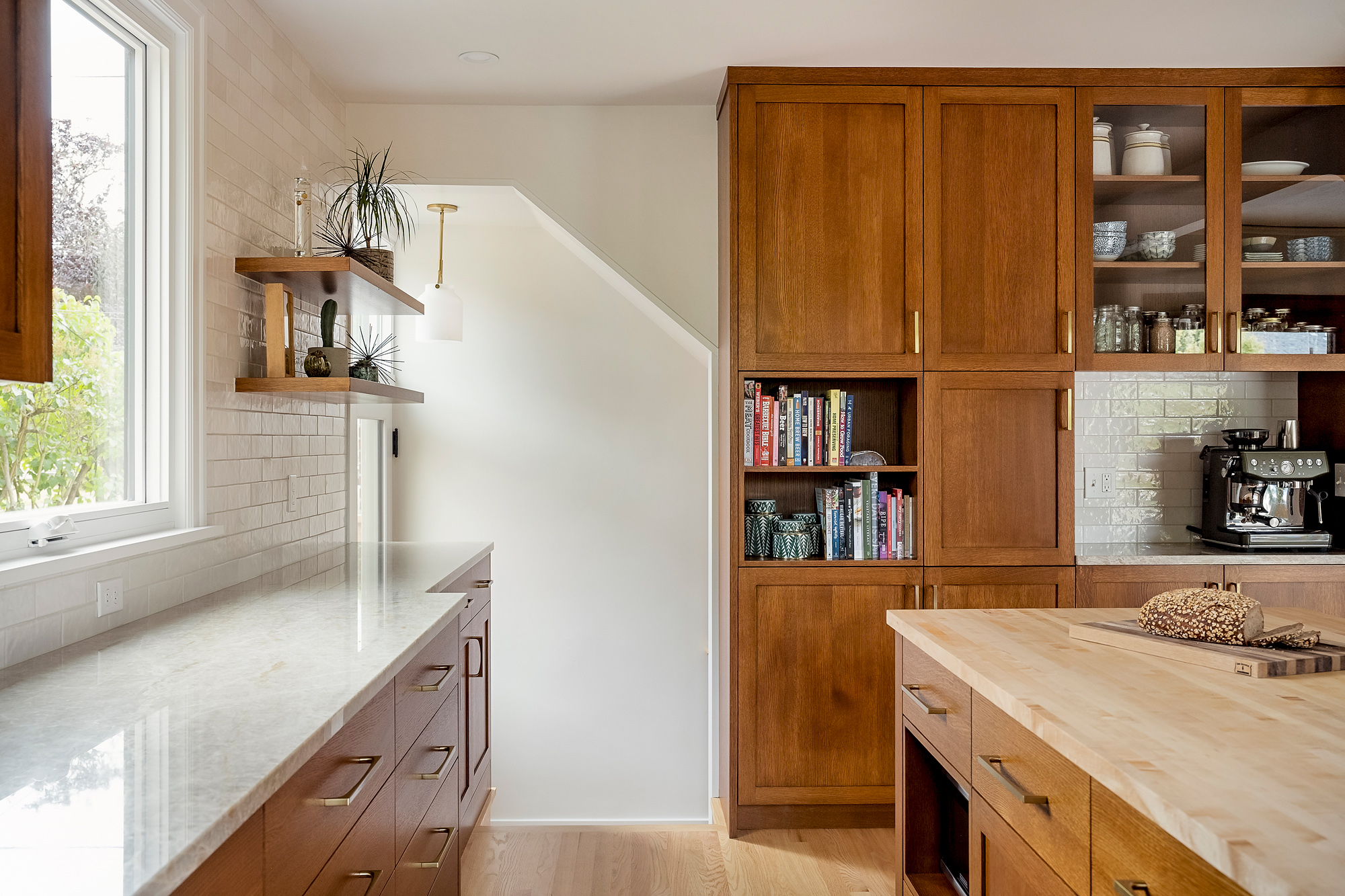 Built-in along the stair wall with pantry storage, open bookshelves, and glass-front upper cabinets, Rose City Kitchen by Tweto Architecture