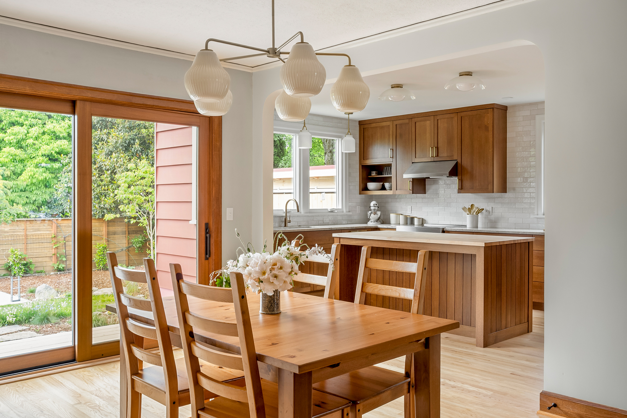 Dining room with new oversize sliding glass door to the backyard garden, kitchen and island visible through the widened opening, Rose City Kitchen by Tweto Architecture