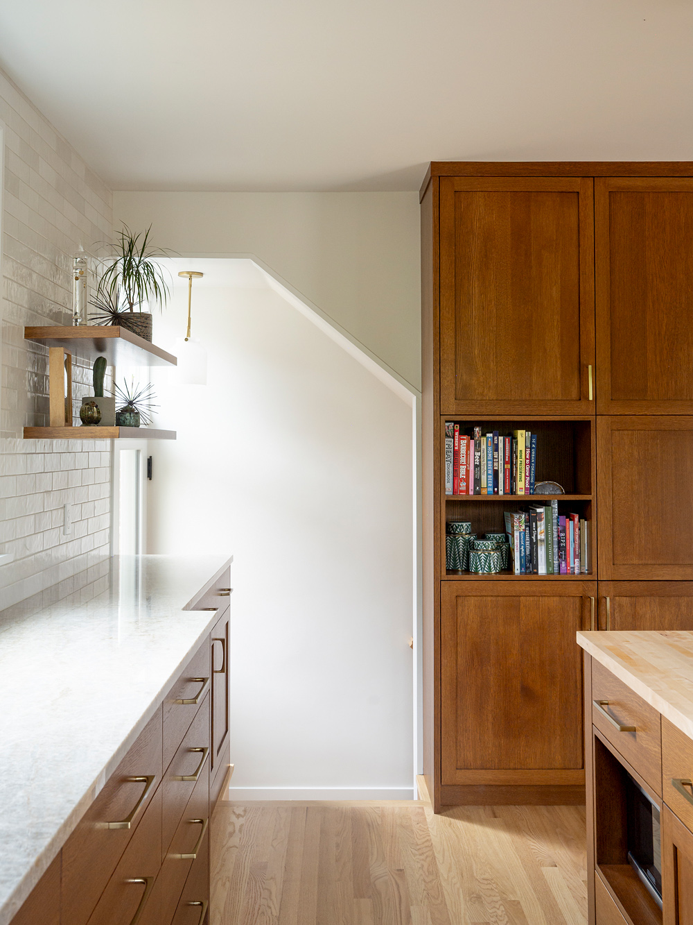 Transition at the stair landing to the basement living space, with pendant, open shelves, and pantry built-in alongside, Rose City Kitchen by Tweto Architecture