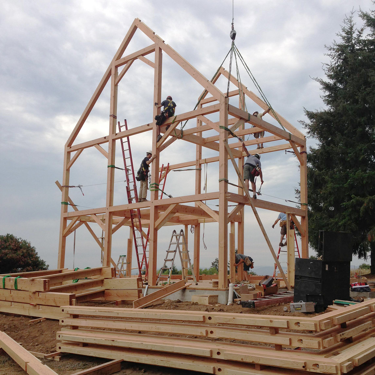Timber frame crew raising the structural frame of a new home on a rural Oregon site, North Plains Timber Frame by Tweto Architecture